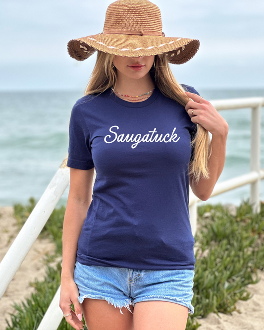 Woman wearing a navy blue t-shirt with 'Saugatuck' text at the beach.